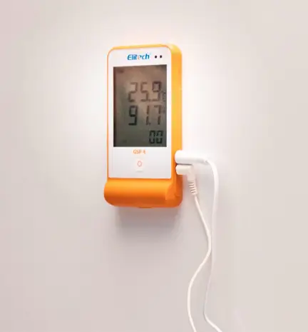 Um datalogger laranja na parede conectado com alguns fios brancos mostrando dados